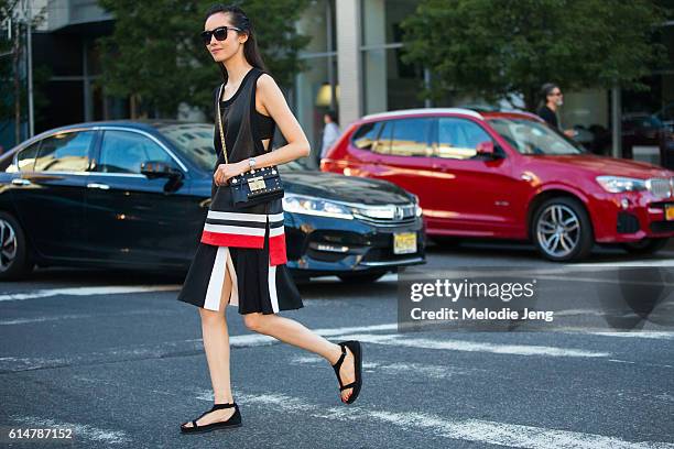 Chinese model Fei Fei Sun wears a sportwear-style black sleevless top with white and red stripes, a black pleated skirt with a white stripe, and a...