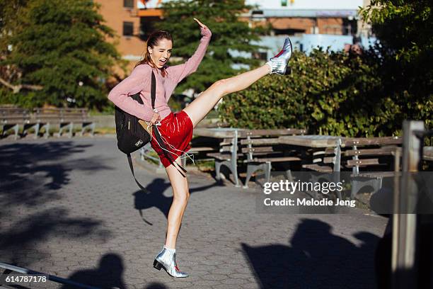 American model Teddy Quinlivan throws a kick and wears a pink sweater, a red patent leather mini skirt, silver Modern Vice booties, and a black...