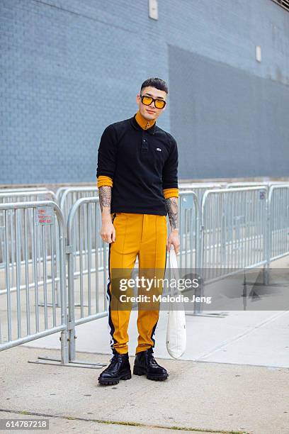 Korean model Noma Han attends the Lacoste show in a black Lacoste polo over an orange turtleneck knit, orange trousers, orange retro-style...