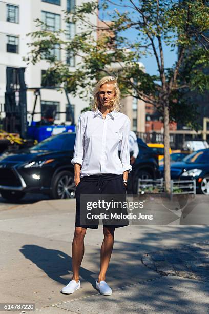 Model Aymeline Valade attends the Lacoste show at Spring Studios in a tomboy style white Lacoste button-up top, black sporty shorts, white sneakers...