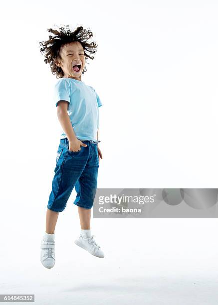 little boy jumping isolated on white background - smiling boy in tshirt stockfoto's en -beelden