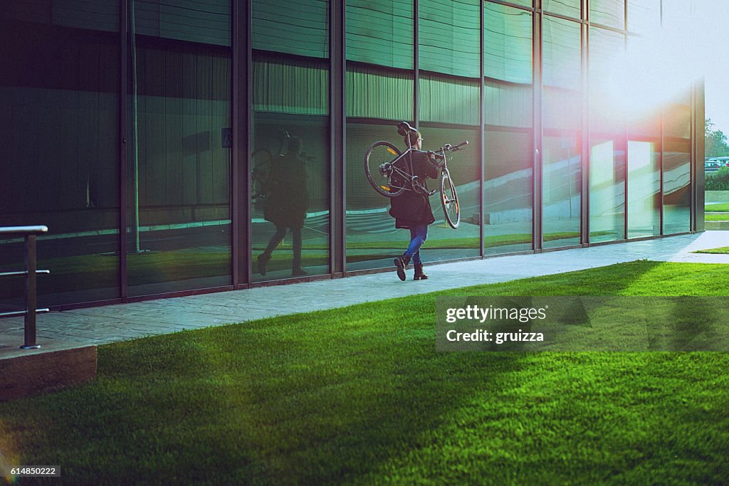 Handsome man carrying bicycle beside the modern office building