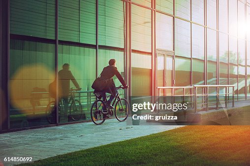 Hübscher Mann mit dem Fahrrad neben dem modernen Bürogebäude Hübscher Mann mit dem Fahrrad neben dem modernen Bürogebäude