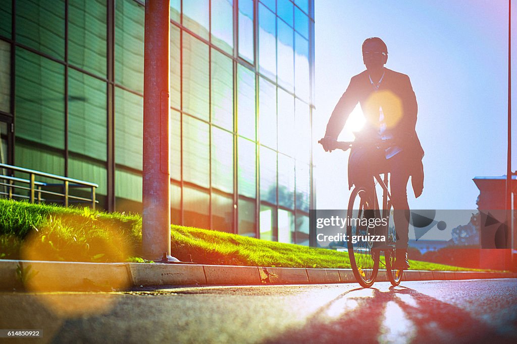 Handsome man riding bicycle beside the modern office building