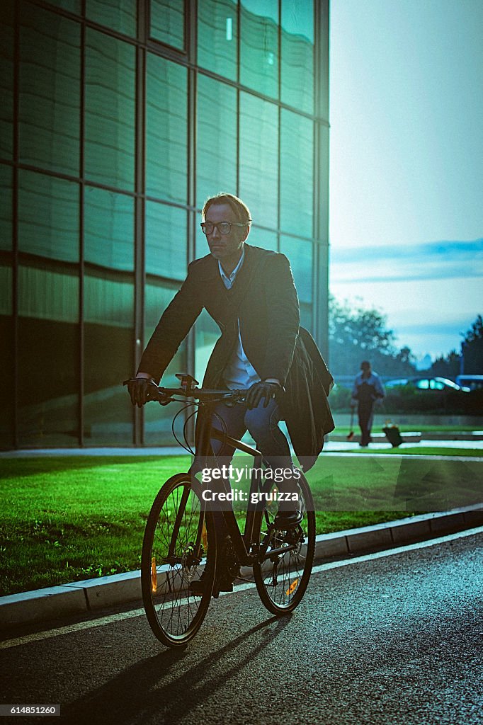 Handsome man riding bicycle beside the modern office building