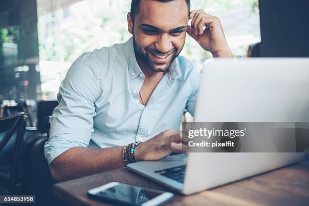 joven usando una computadora portátil  - elearning man fotografías e imágenes de stock