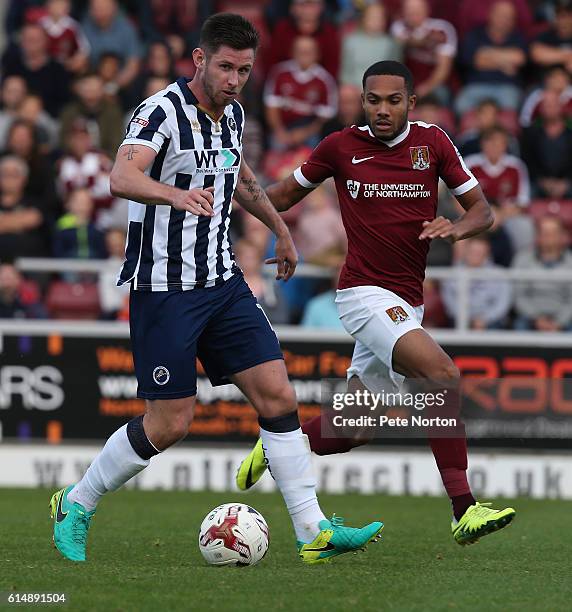 Calum Butcher of Millwall looks to play the ball watched by Kenji Gorre of Northampton Town during the Sky Bet League One match between Northampton...