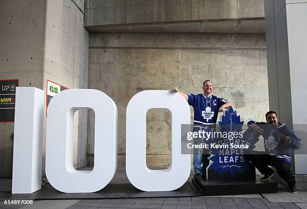 Toronto Maple Leafs fans pose on a sign commemorating the 100th season of the team before the home opener against the Boston Bruins at the Air Canada...