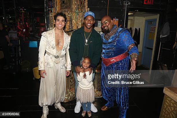 Adam Jacobs as "Aladdin", NY Giants Victor Cruz, daughter Kennedy Cruz and James Monroe Iglehart as "The Genie" pose backstage at "Disney's Aladdin"...