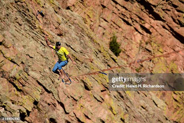 Taylor VanAllen makes the FA, or First Across, on a high-line from the Wind Tower rock formation to the Bastille rock formation 450 feet off the...