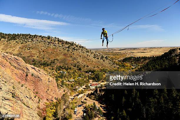 Taylor VanAllen works his way down the rope to walk on a high-line from the Wind Tower rock formation to the Bastille rock formation in Eldorado...