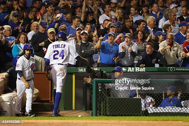 Dexter Fowler of the Chicago Cubs celebrates at the dugout with manager Joe Maddon after scoring a run in the first inning against the Los Angeles...