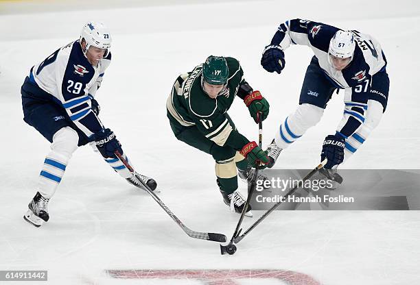 Teemu Pulkkinen of the Minnesota Wild passes the puck away from Patrik Laine and Tyler Myers of the Winnipeg Jets during the first period of the game...