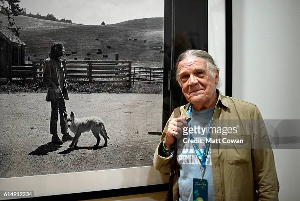 Photographer Henry Diltz poses with his photos in the Photography Experience during Desert Trip at the Empire Polo Field on October 15, 2016 in...