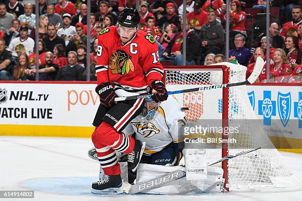 Jonathan Toews of the Chicago Blackhawks gets out of the way of the puck that makes it past goalie Marek Mazanec of the Nashville Predators, for the...