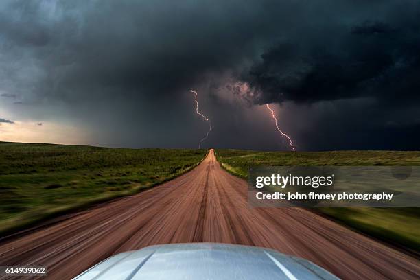High speed storm chasing, taken from the roof of a moving car off road with double lightning bolts ahead. Colorado, USA.