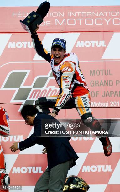 Repsol Honda Team's Spanish rider Marc Marquez gestures on the podium as he celebrates his fifth world champion after his victory at the MotoGP race...