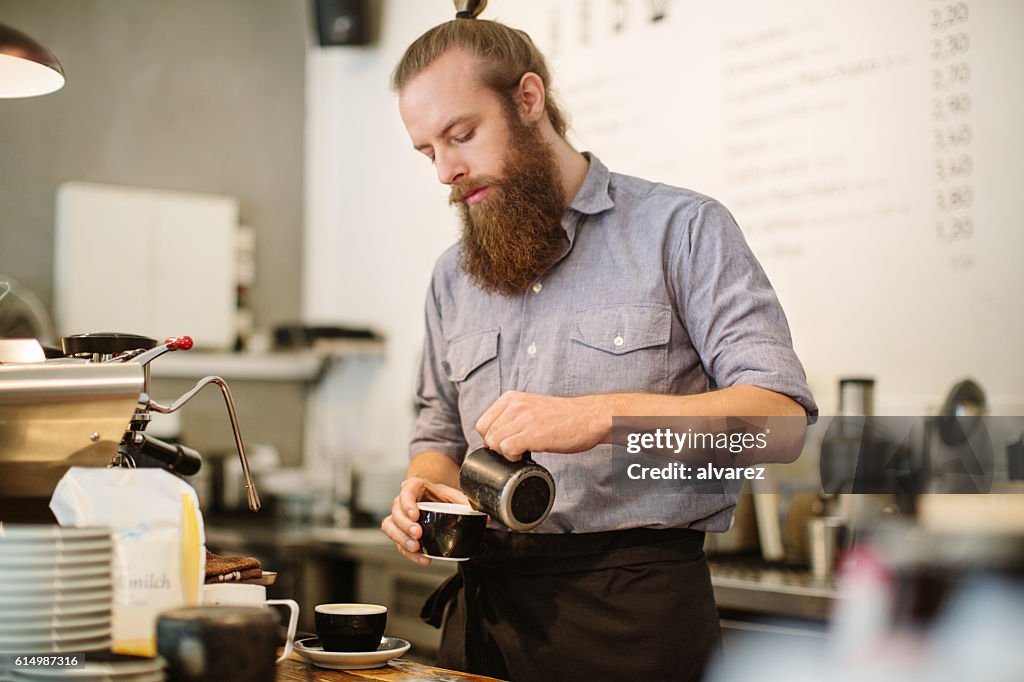 Young man preparing coffee at cafe counter