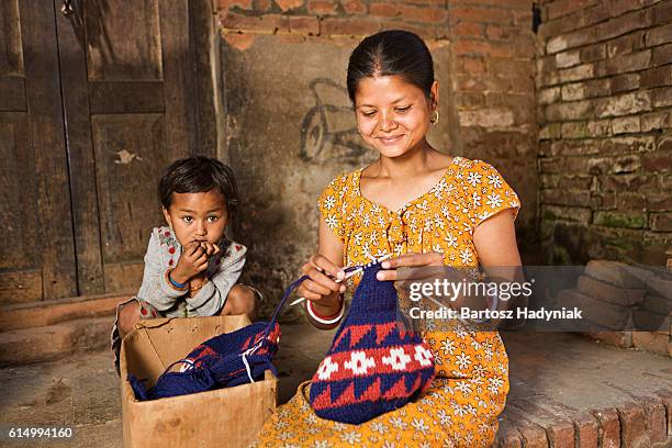 junge nepalesische frau stricken wollmütze in bhaktapur - nepali mother stock-fotos und bilder