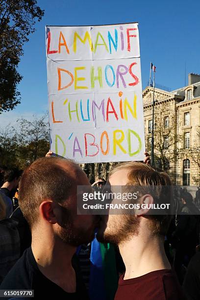 Men kiss one another next to a sign reading "The manif outside, the human first of all" during a "kiss-in" demonstration in defense of marriage...