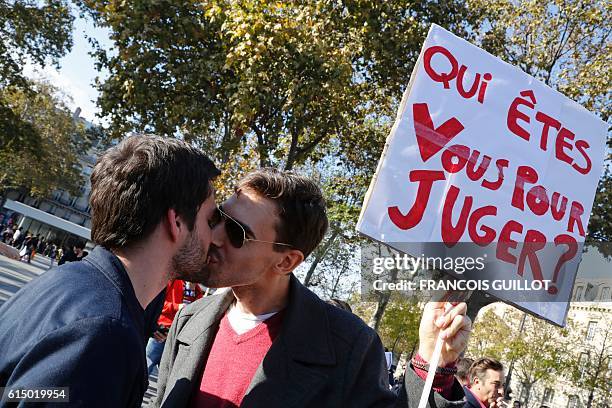 Men kiss one another while holding a sign reading "Who are you to judge?" during a "kiss-in" demonstration in defense of marriage equality, and...
