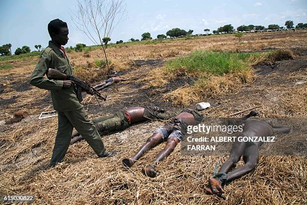 Graphic content / A soldier of the Sudan People Liberation Army patrols next to the bodies of dead rebel soldiers in Lelo, outside Malakal, northern...