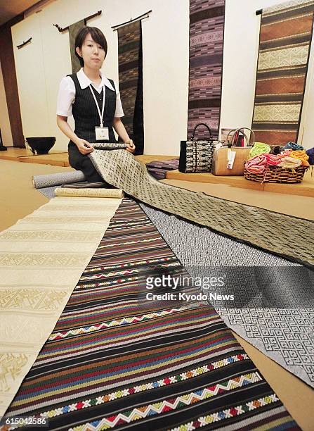 Japan - A staffer at Kyoto kimono wholesaler Omiya Co. Shows obi sashes for kimono on Sept. 21 made of hand-woven textiles by Laotian women. The obis...