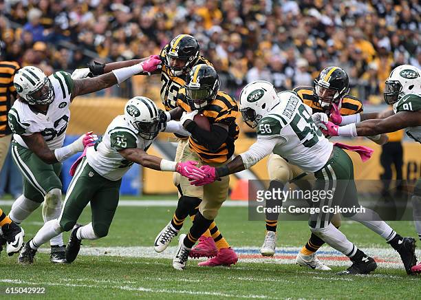 Running back Le'Veon Bell of the Pittsburgh Steelers runs with the football as offensive guard Ramon Foster and tight end Jesse James block against...