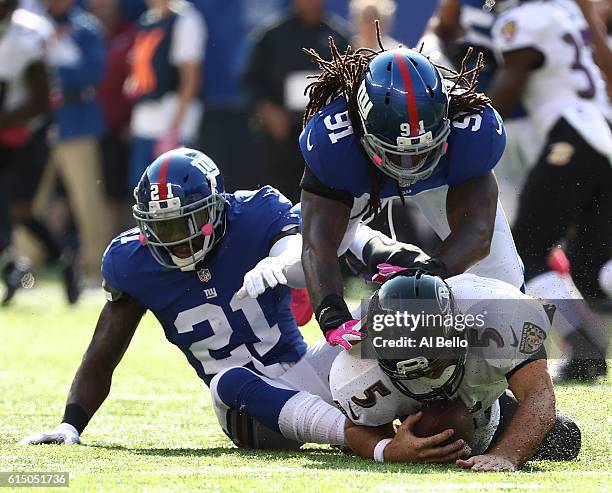 Joe Flacco of the Baltimore Ravens is sacked by Kelvin Sheppard and Landon Collins of the New York Giants during their game at MetLife Stadium on...