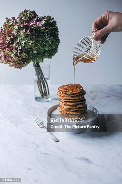 stack of vegan banana pancakes stack and woman"u2019s hand pouring maple syrup - syrup drizzle stock pictures, royalty-free photos & images