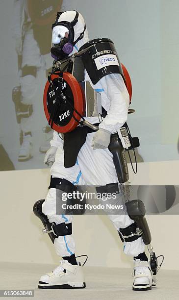 Japan - A person walks wearing a new model of the HAL robotic suit, with weight totaling 40 kilograms on the front and back, as the model is unveiled...