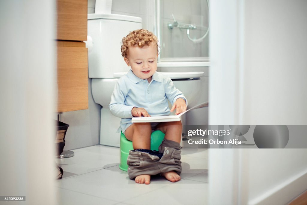 Kind sitzt auf der Toilette