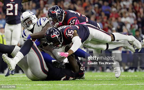 Whitney Mercilus of the Houston Texans, Kevin Johnson, and Eddie Pleasant tackle Frank Gore of the Indianapolis Colts during the fourth quarter at...