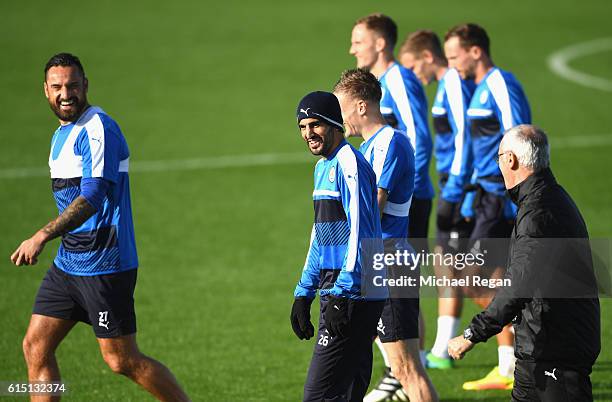 Claudio Ranieri, Manager of Leicester City jokes with Riyad Mahrez and Marcin Wasilewski during a Leicester City training session ahead of their UEFA...