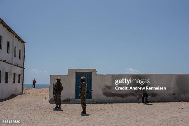 Somali police officers and Ugandan soldiers deployed with the African Union Mission in Somalia stand guard outside a school during a visit by...