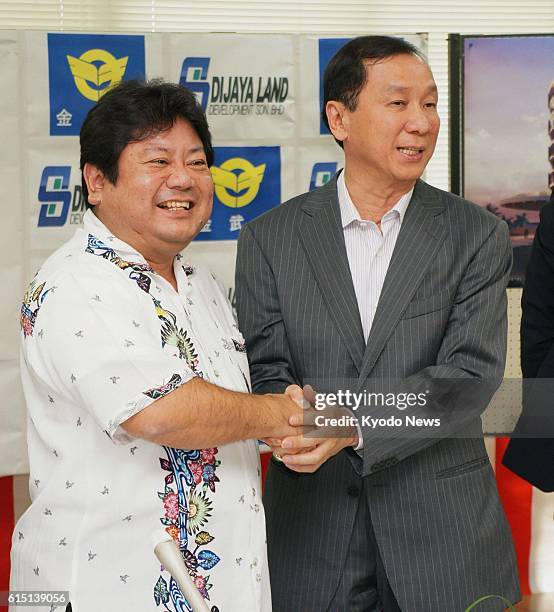 Kin, Japan - Kin Mayor Tsuyoshi Gibu and Tan Chee Sing, chief executive officer of Malaysian developer Dijaya Corp., shake hands in the town in...
