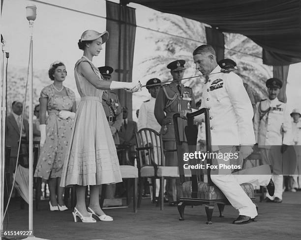 Queen Elizabeth II knighting Air Marshal Claude Pelly , Commander-in-Chief of the RAF Middle East Air Force, by touching his shoulder with a...