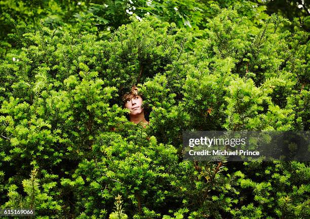 boy standing in bush - se cacher photos et images de collection