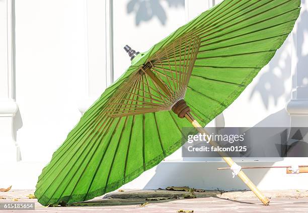 green oil-paper umbrella and white wall with tree shade - papierschirm stock-fotos und bilder