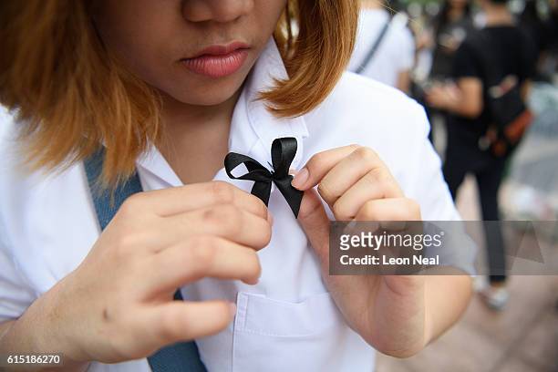 Woman pins a black tribute ribbon to her blouse in Sanam Luang on October 17, 2016 in Bangkok, Thailand. Thailand's King Bhumibol Adulyadej died at...