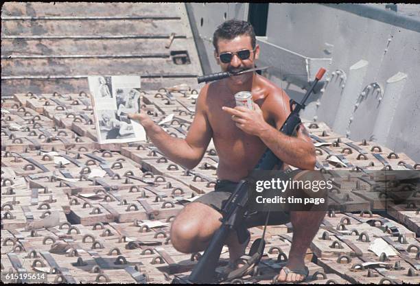 Soldier on board a landing ship filled with ammunition on its way along the Huong Giang river , to the central Vietnamese city of Hue. He holds a...