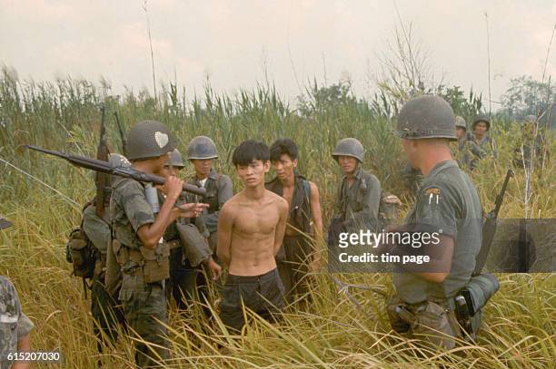 Group of South Vietnamese army soldiers and an American soldier with two captured Vietcong suspects. | Location: Plaines des Joncs, South Vietnam.