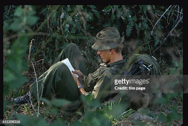 An American radioman takes a break and reads, near Bien Hoa, Vietnam. 1965. | Location: Near Bien Hoa, Vietnam.