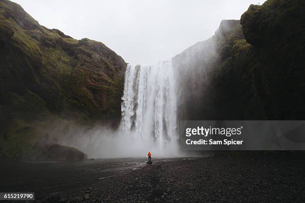 man looking at view of epic waterfall in iceland - iceland waterfall stock-fotos und bilder