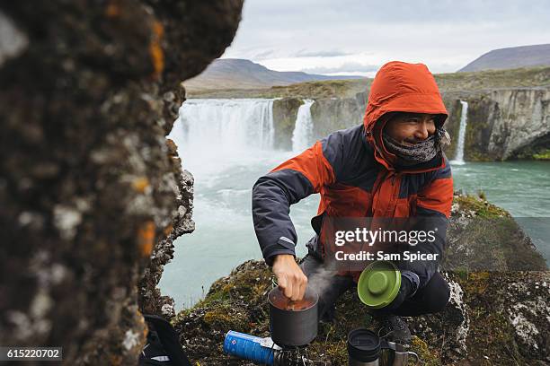 man preparing camp food during camping trip - camping stove stockfoto's en -beelden