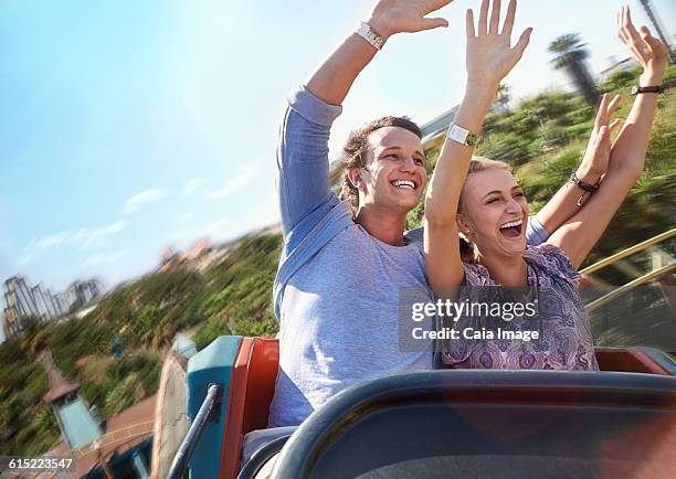 exhilarated young couple riding amusement park ride - young woman screaming on a rollercoaster stock pictures, royalty-free photos & images