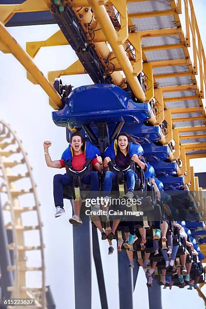 young man cheering on amusement park ride - young woman screaming on a rollercoaster stock-fotos und bilder