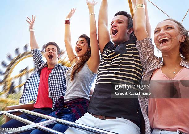 cheering friends riding amusement park ride - young woman screaming on a rollercoaster stock-fotos und bilder