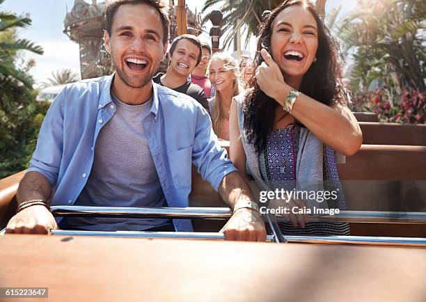 enthusiastic young couple riding amusement park ride - young woman screaming on a rollercoaster stock-fotos und bilder