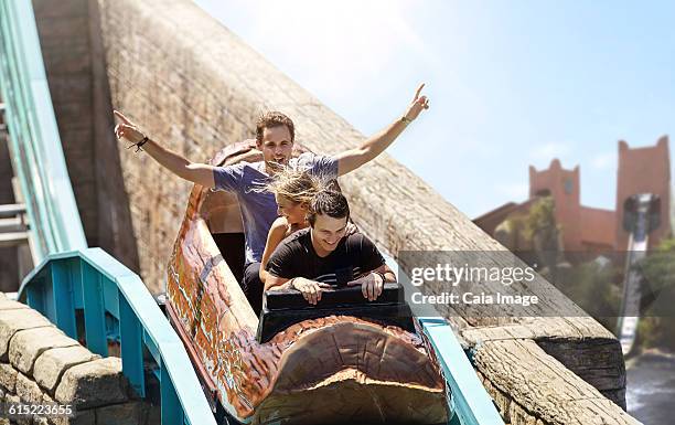 young man cheering on log amusement park ride - young woman screaming on a rollercoaster stock-fotos und bilder